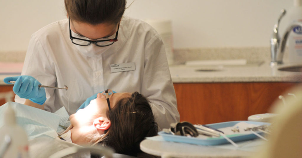 A Dentist examining the teeth of a patient.